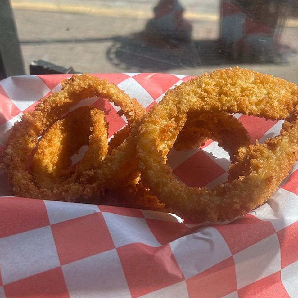 Golden-brown onion rings from My Brothers Place Parkville, served in a red and white checkered paper.