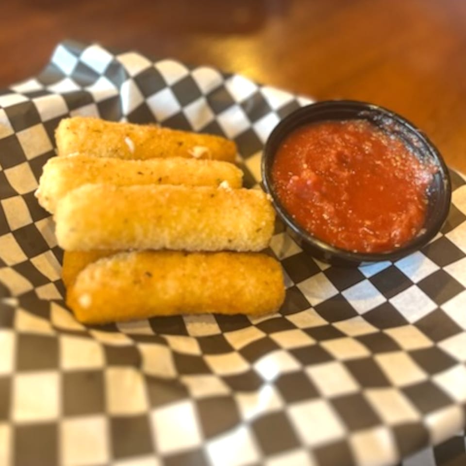 Golden-brown mozzarella sticks with a side of red marinara sauce on a checkered paper liner.