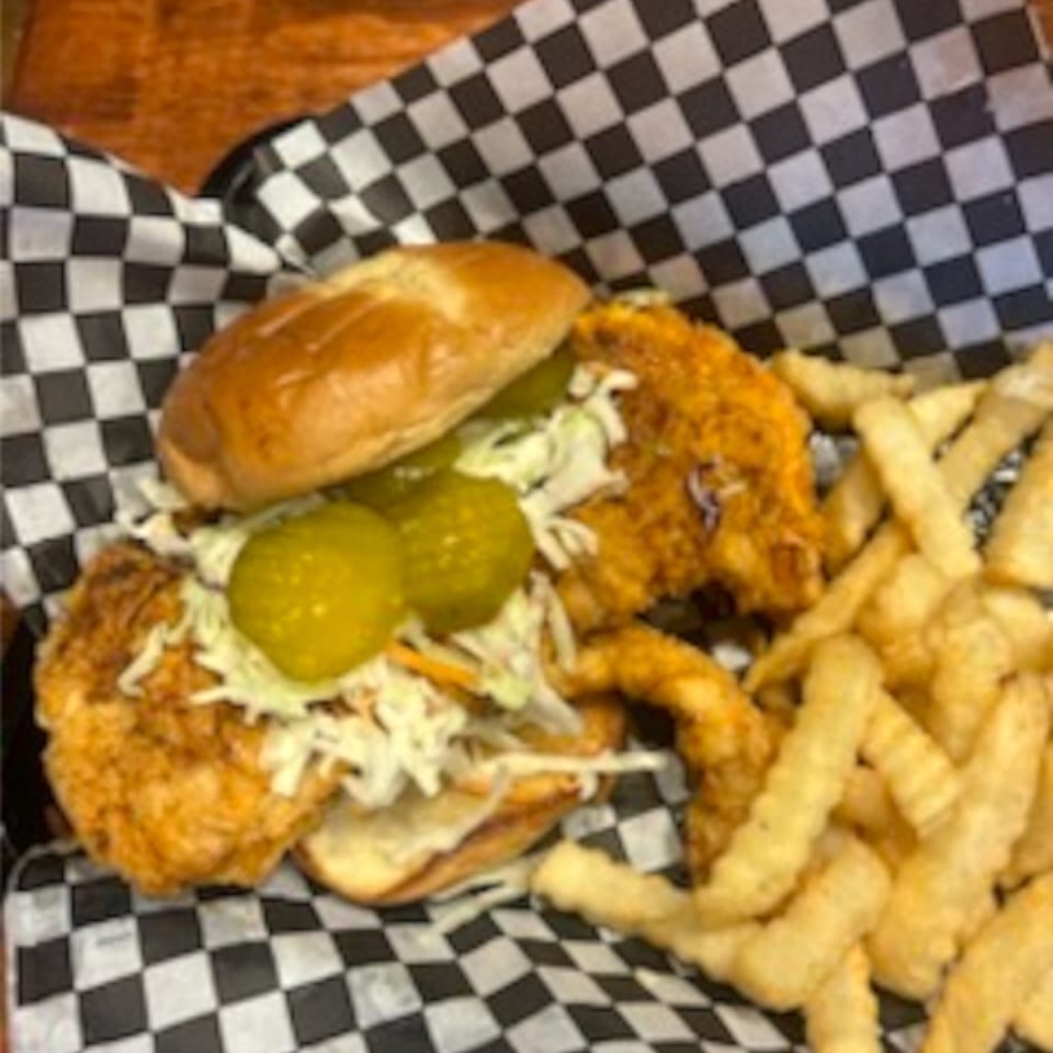 My Brothers Place fried chicken sandwich with coleslaw, pickles, and crinkle-cut fries.