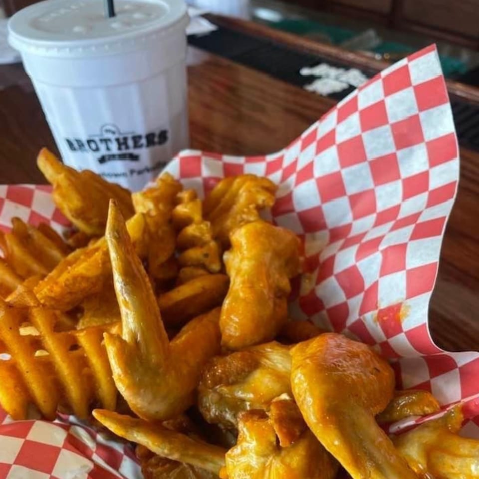 My Brothers Place Parkville's chicken wings and waffle fries in a red and white checkered basket.